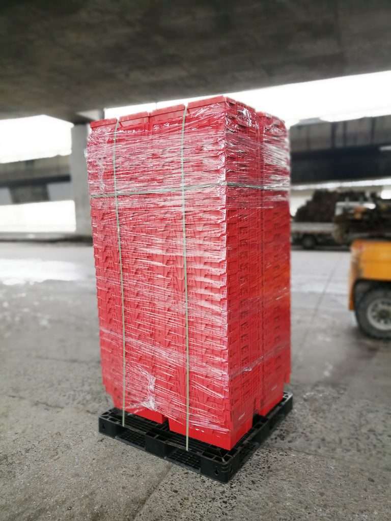 Nested red plastic moving boxes are packed on a black pallet.